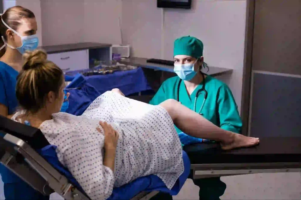 Pregnant woman in labor being assisted by doctors and nurses during normal delivery in a hospital labor room.